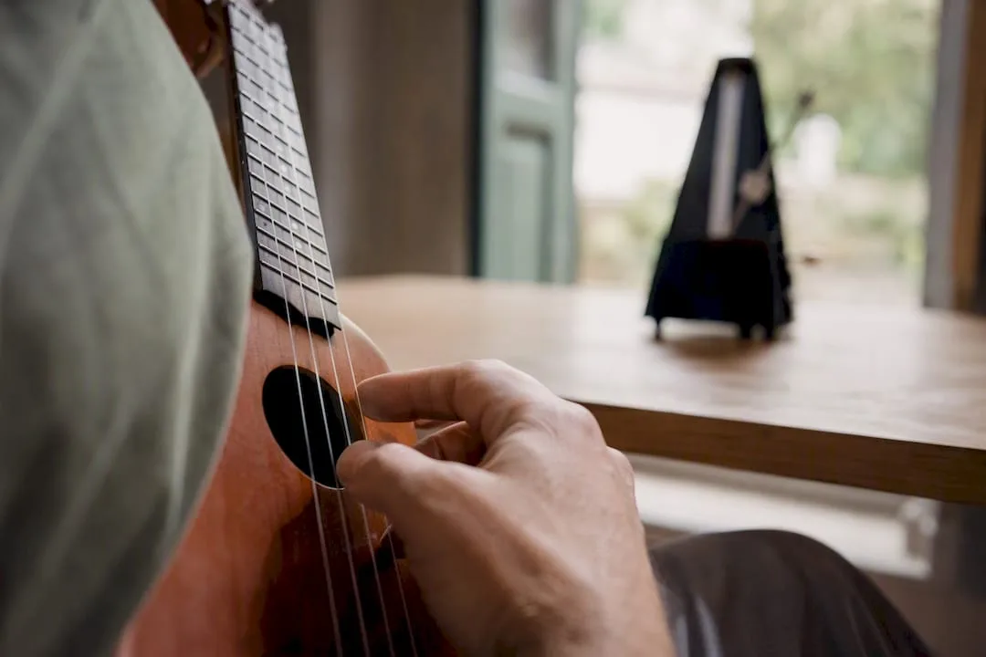 Rechterhand die met vingers de open snaren van een ukelele bespeelt met een metronoom