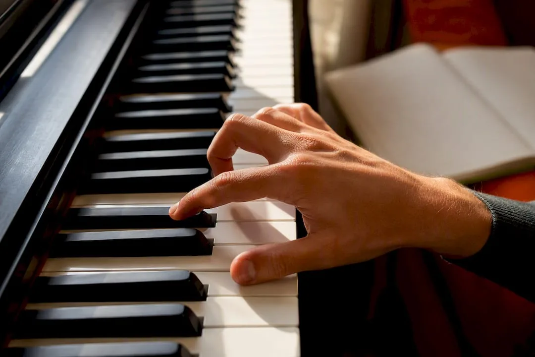 Hand die een akkoord in eerste omkering op de piano speelt