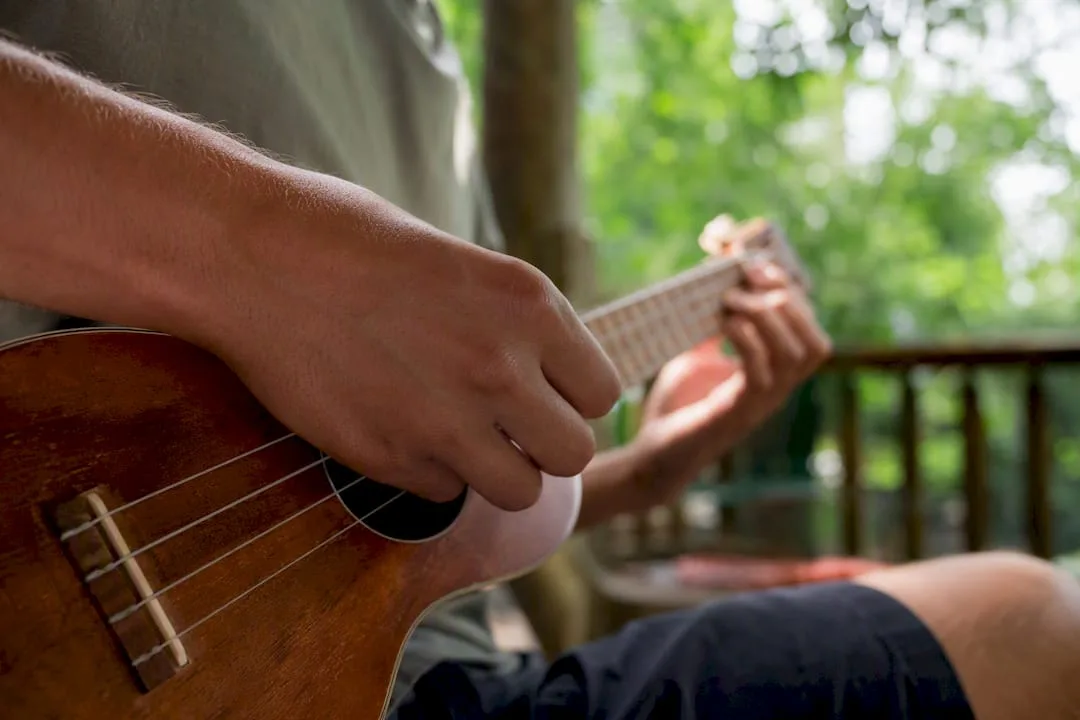 Hand die langzaam over de snaren van een ukelele strijkt